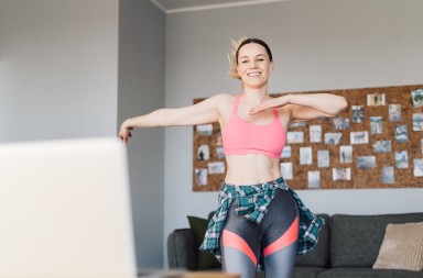 Active young woman in sportswear clothes dancing moves in living room with cozy, modern interior sunny day, feels happy, enjoy life concept. Occupation during isolation at home.